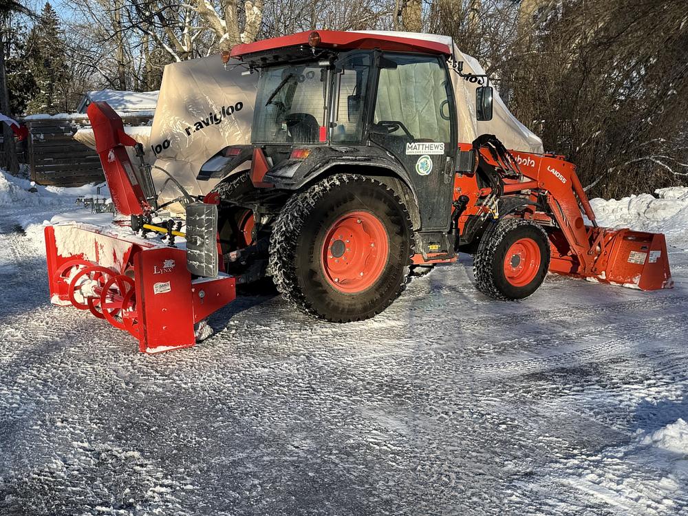 Our tractor with a front loader and a rear-mounted snowblower, on a cleared snowy driveway